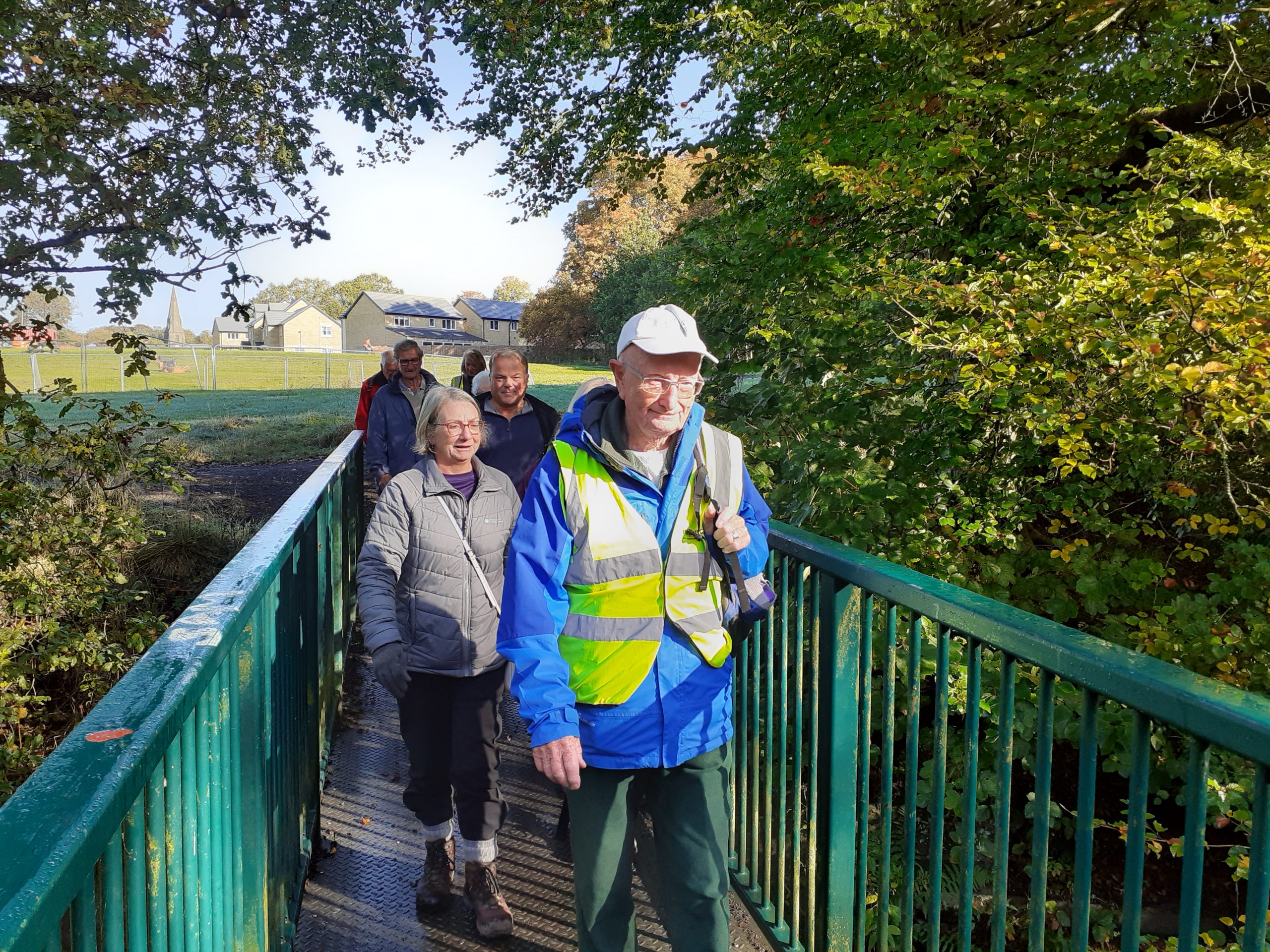 Male walker followed by group, walking across abridge