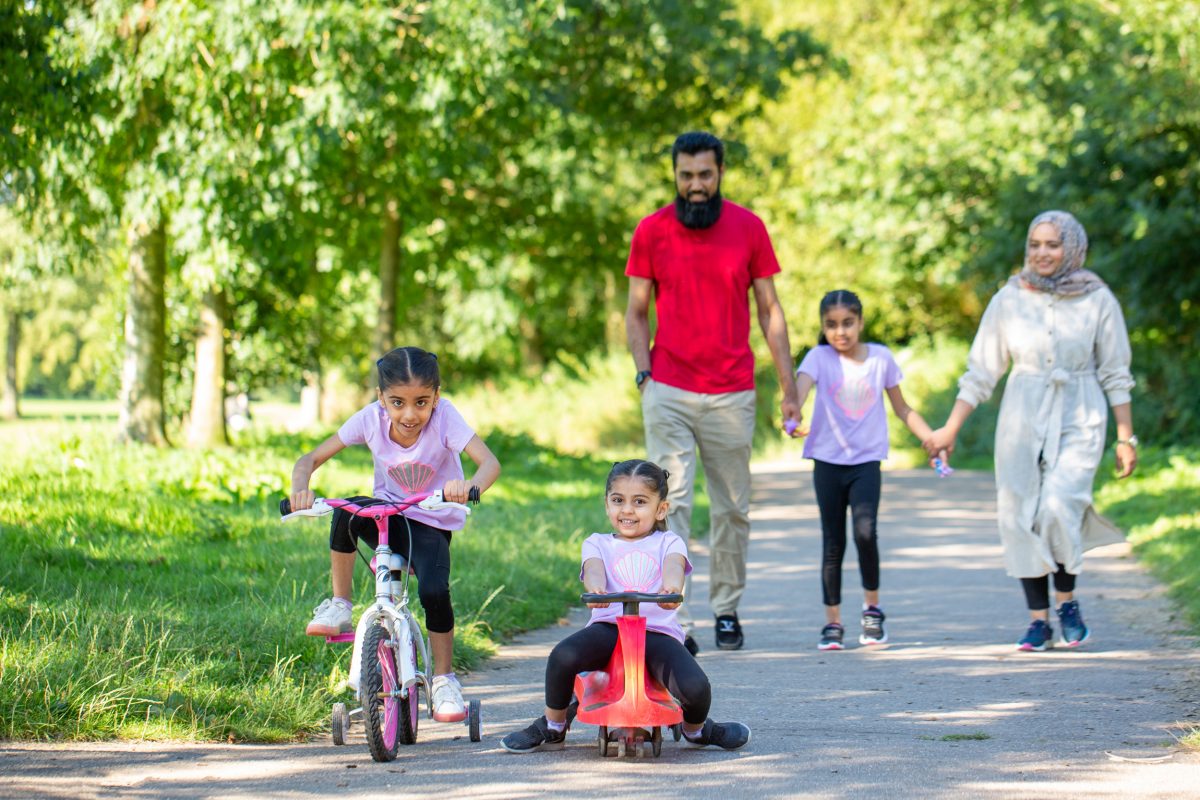 Asian Family on a walk, with two small children cycling and scooting